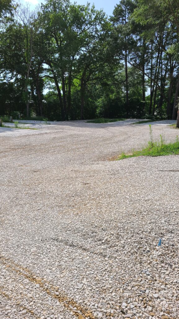 Empty RV park with clean concrete pads and full hookup pedestals on a sunny day, no RVs present