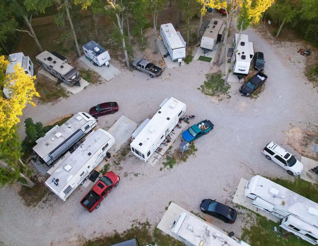 Aerial view of a fully occupied RV park with all sites filled, surrounded by calm and quiet, under sunny skies